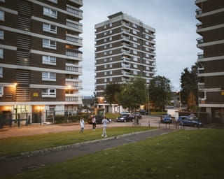 Kinderen spelen buiten in het schemerdonker tussen twee hoge flats nabij de grens.