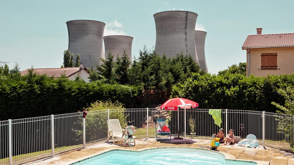 Foto van Italiaanse fotograaf Andrea Pugiotto. Op de voorgrond een zwembad in de achtertuin van een Frans gezin, daar vlak achter 4 grote koeltorens van een energie centrale. 