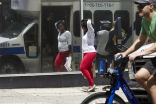 vrouw met lange haren, wit shirt en rode legging loopt langs en checkt haar looks.