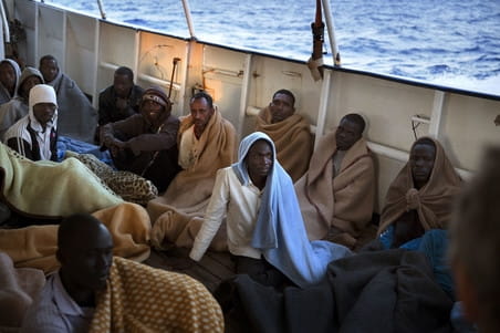 Mannen zitten aan boord van de Golfo Azzurro nadat zij gered zijn ten noorden van Zuwarah op 21 juni 2017. Foto: Emilio Morenatti / AP