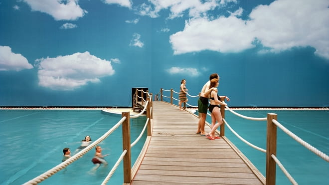 Mensen in zwemwaar voor een muur met daarop een afbeelding van de lucht