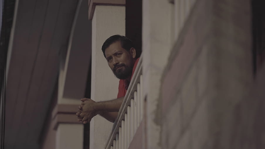 Een portret van Carlos Choc, genomen terwijl hij op de rand van zijn veranda leunt.