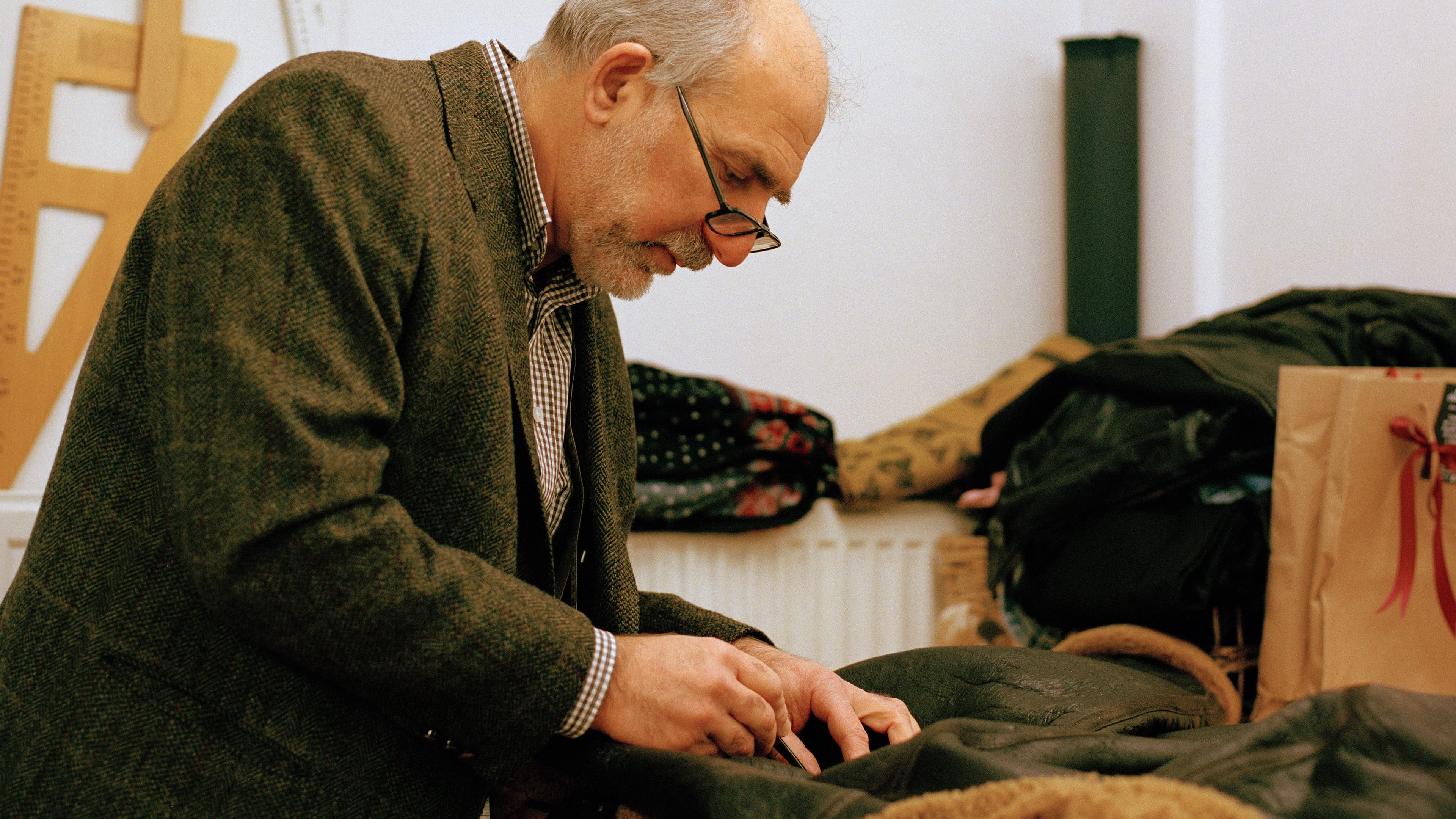 Foto van de Turkse kleermaker Atilla (van de winkel Amsterdam Tailors) aan het werk in zijn atelier. Atilla is bezig een leren jack te repareren.