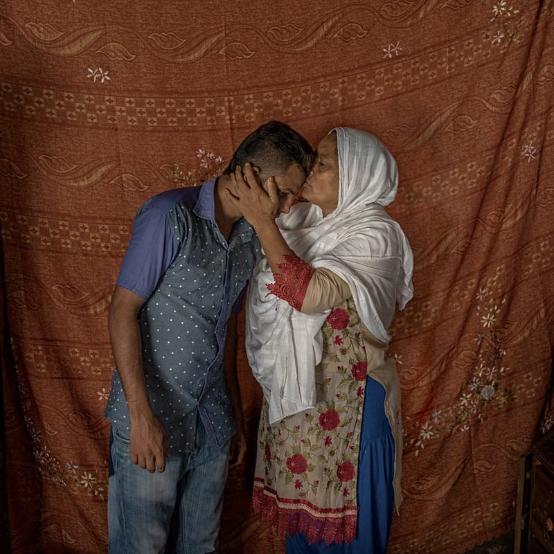 Shobuj Hosain Ridoy wordt gekust door zijn trotse moeder. Hij verloor zijn baan omdat hij wekenlang hielp bij de reddingswerkzaamheden na het instorten van Rana Plaza, en gedurende die tijd niet op zijn werk verscheen. Uit de serie After Rana Plaza door Ismail Ferdous. 