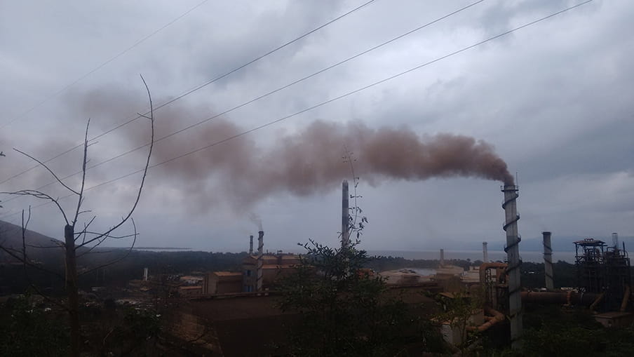 Rode rook komt uit de schoorstenen van de ijzerertsmijn in El Estor. 