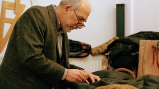 Foto van de Turkse kleermaker Atilla (van de winkel Amsterdam Tailors) aan het werk in zijn atelier. Atilla is bezig een leren jack te repareren.