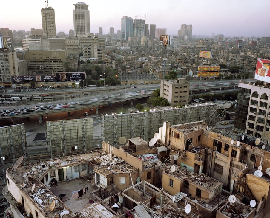 Een groep mensen woont op de bovenste verdieping van woonhuizen, achter de billboard op de Zes Oktober ring in Caïro. Foto: Mark Nozeman