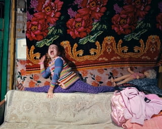Foto Uit de serie Child’s Play door fotograaf Mark Neville, waarop een meisje met haar pop te zien is.