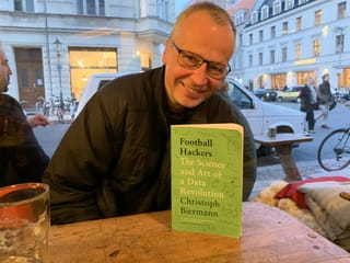 Journalist Christoph Biermann poseert met zijn boek 'Football Hackers' in een café in Berlijn-Mitte.