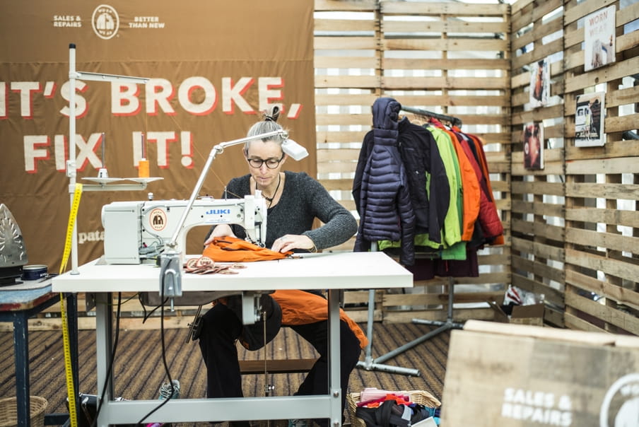 Een medewerker van Patagonia repareert een kledingstuk achter de naaimachine.