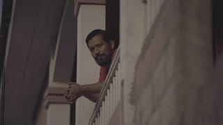 Een portret van Carlos Choc, genomen terwijl hij op de rand van zijn veranda leunt.