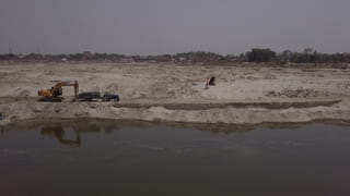Een graafmachine graaft zand weg bij de Garra-rivier.