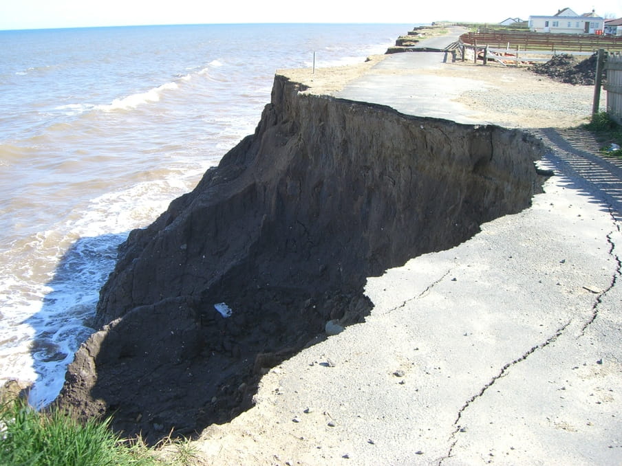Een stuk weg langs de kust is weggeslagen door de golven.