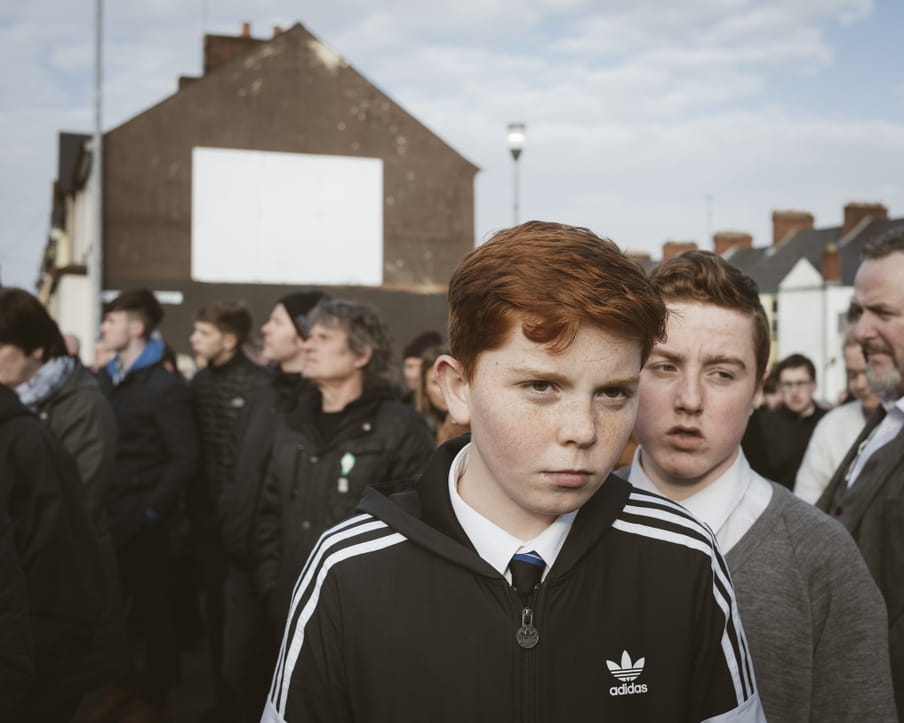 Een portret van een Katholieke jongen in een menigte bezoekers van de begrafenis van Martin McGuinness.