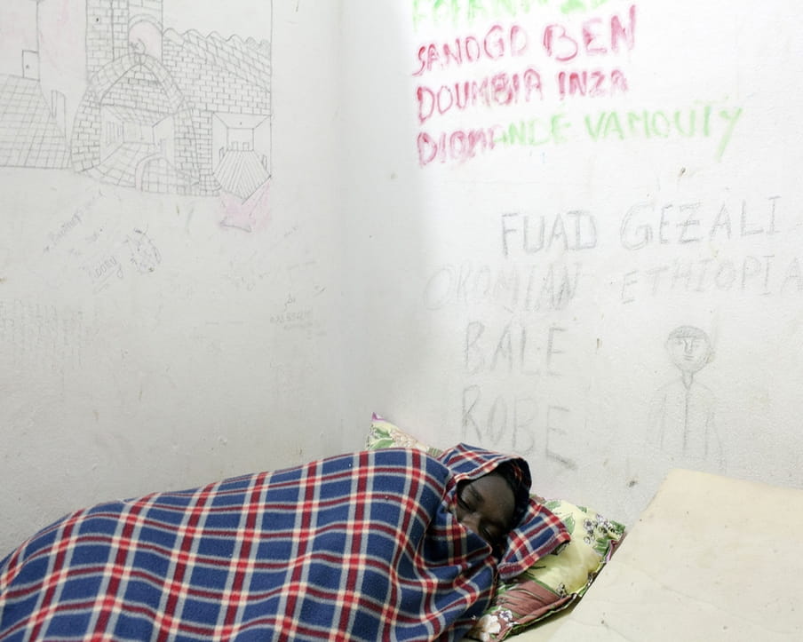Een Ethiopische migrant slaapt in het Al Khoms-detentiecentrum in Libië, november 2015. Foto: Magnum Photos / HH